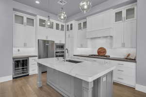 Kitchen with wine cooler, gray cabinets, glass insert cabinets, decorative backsplash, and pendant lighting