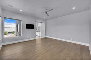 Unfurnished bedroom with a barn door, light wood-style floors, a ceiling fan, recessed lighting, and ensuite bath