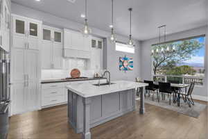 Kitchen featuring hanging light fixtures, gray cabinets, tasteful backsplash, white cabinets, and dark wood-type flooring