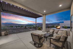 Patio terrace at dusk with a patio, an outdoor living space with a fire pit, and a mountain view