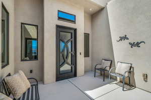 Entrance to property with stucco siding and a patio area