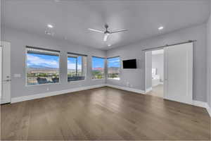 Unfurnished living room with a barn door, ceiling fan, light wood-type flooring, and recessed lighting