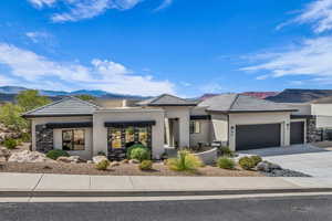 Prairie-style home featuring a mountain view, stucco siding, driveway, a garage, and stone siding
