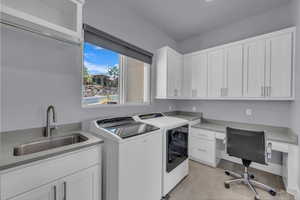 Laundry area featuring separate washer and dryer, light tile patterned flooring, cabinet space, and a desk