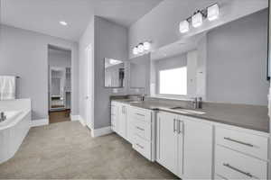 Bathroom with double vanity, a bath, recessed lighting, and light tile patterned floors