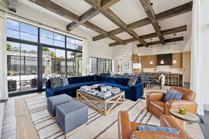 Living room featuring coffered ceiling, beam ceiling, a chandelier, wood finished floors, and a towering ceiling