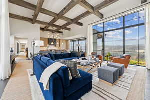 Living room featuring coffered ceiling, beam ceiling, a chandelier, a mountain view, and wood finished floors