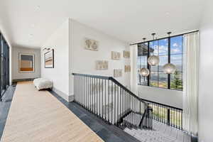 Corridor with an upstairs landing, expansive windows, and dark tile patterned floors