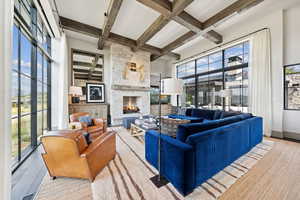 Living room featuring beamed ceiling, coffered ceiling, a fireplace, and wood finished floors
