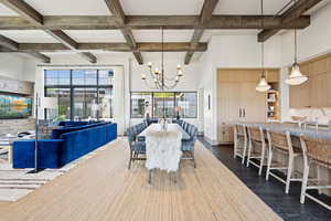 Dining room with beamed ceiling, coffered ceiling, a chandelier, a towering ceiling, and dark wood-type flooring