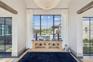 Doorway with tile patterned floors and beam ceiling