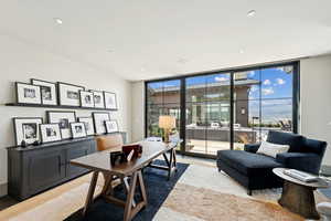 Home office with floor to ceiling windows, light wood-style floors, and recessed lighting