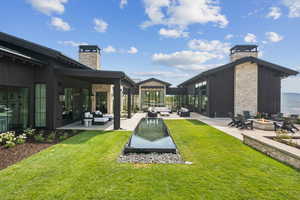 View of green lawn featuring a patio and an outdoor living space with a fire pit