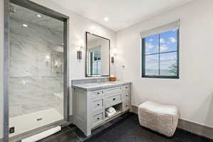 Full bathroom with a marble finish shower, vanity, and dark tile patterned floors