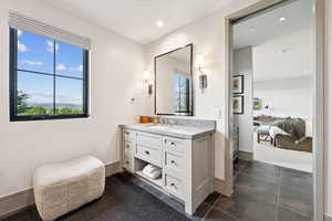 Ensuite bathroom featuring vanity, dark tile patterned floors, and recessed lighting