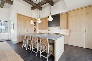Kitchen with light brown cabinetry, modern cabinets, beamed ceiling, a breakfast bar, and hanging light fixtures