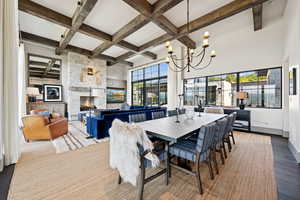 Dining room with beamed ceiling, coffered ceiling, plenty of natural light, wood finished floors, and a stone fireplace