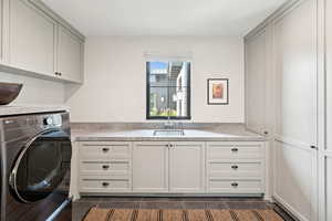 Laundry room with washer / clothes dryer, dark tile patterned floors, and cabinet space
