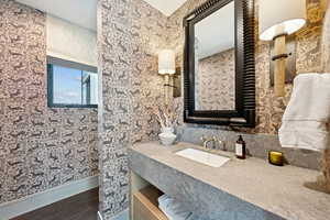 Bathroom featuring wallpapered walls, vanity, and dark wood-type flooring
