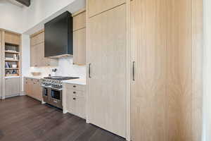 Kitchen featuring light brown cabinets, modern cabinets, range with two ovens, open shelves, and range hood