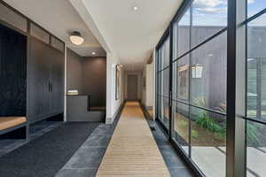 Hallway with floor to ceiling windows, dark tile patterned floors, and recessed lighting