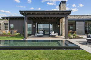 Back of house with a patio, a yard, stone siding, and an outdoor hangout area