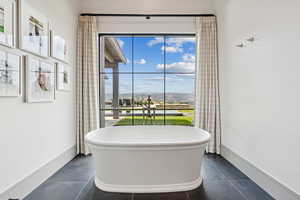 Full bath with a freestanding tub and dark tile patterned floors