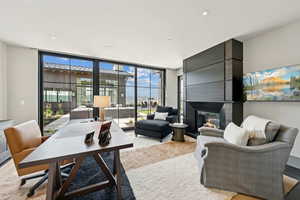 Living area featuring floor to ceiling windows, a large fireplace, a desk, and recessed lighting
