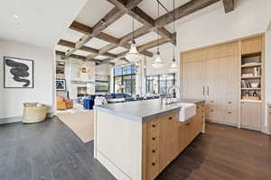 Kitchen with light brown cabinetry, dark wood-style flooring, coffered ceiling, beam ceiling, and a fireplace