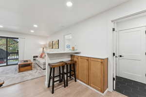 Bar with light countertops, brown cabinets, recessed lighting, and light wood-style flooring