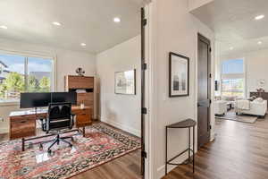 Office with a textured ceiling, wood finished floors, and recessed lighting