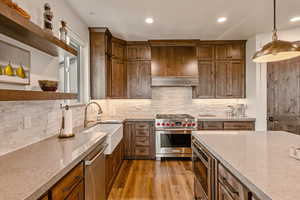 Kitchen with open shelves, tasteful backsplash, light wood-type flooring, light stone counters, and stainless steel appliances