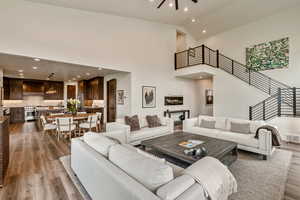 Living area with recessed lighting, light wood-style floors, high vaulted ceiling, and stairway