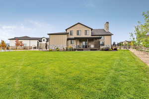 Back of property featuring a fenced backyard, stone siding, board and batten siding, and a chimney