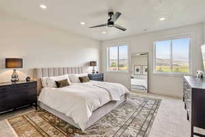 Bedroom featuring light colored carpet, a ceiling fan, recessed lighting, a textured ceiling, and a mountain view