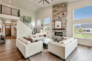 Living area with wood finished floors, high vaulted ceiling, a fireplace, stairway, and recessed lighting