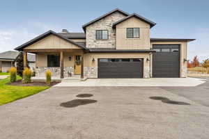 Craftsman-style home featuring stone siding, board and batten siding, a porch, and asphalt driveway