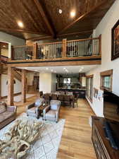 Living room featuring a wooden ceiling with exposed beams, recessed lighting, light wood-type flooring, stairway, and high vaulted ceiling
