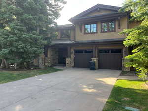 Craftsman inspired home featuring stone siding, concrete driveway, and an attached garage
