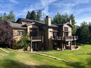 Back of house with a chimney, a yard, and stone siding