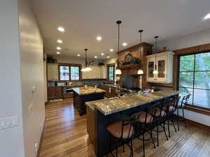 Kitchen featuring dark stone counters, a kitchen breakfast bar, a peninsula, pendant lighting, and recessed lighting