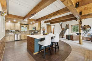 Kitchen with light brown cabinets, a kitchen breakfast bar, open floor plan, decorative backsplash, and stainless steel appliances