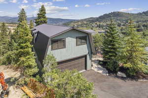 View of front of house with a garage, a mountain view, a metal roof, and driveway