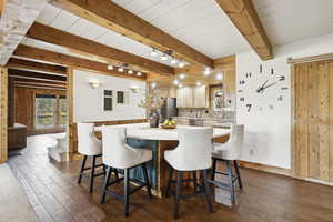 Dining room with dark wood-style floors, beam ceiling, and wooden walls