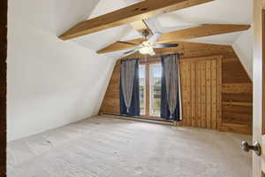 Additional living space featuring wood walls, carpet floors, baseboard heating, and a ceiling fan