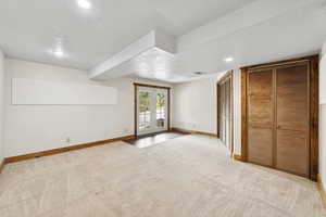Bonus room with a textured ceiling, light carpet, recessed lighting, and french doors