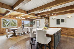 Dining space with wood walls, dark wood-style flooring, and a wooden ceiling with exposed beams