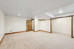 Finished below grade area featuring light colored carpet, recessed lighting, and a textured ceiling