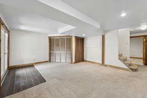 Carpeted empty room with recessed lighting, a textured ceiling, stairs, and wood finished floors
