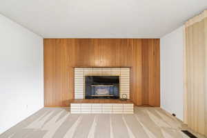 Detailed view of wood walls, carpet, a textured ceiling, and a brick fireplace